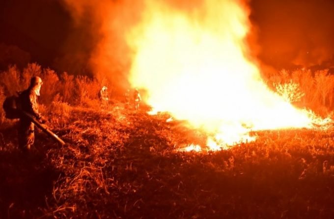 Imagem de grande foco de incêndio no Pantanal com vários combatentes em volta